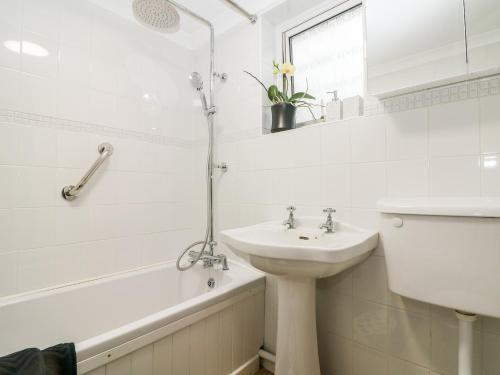 a white bathroom with a sink and a bath tub at Fisherman's Cottage in Pevensey