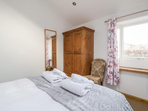 a bedroom with a bed and a chair and a window at The Old Cook House in Penrith