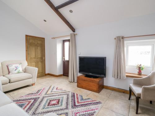 a living room with a tv and a couch and chairs at The Old Cook House in Penrith