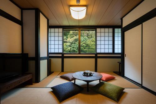 a living room with a table and a window at Onsen Guest House Tsutaya in Hakone