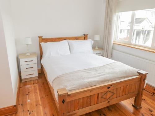 a bedroom with a bed with a wooden frame and a window at Duffy's Cottage in Ballymote