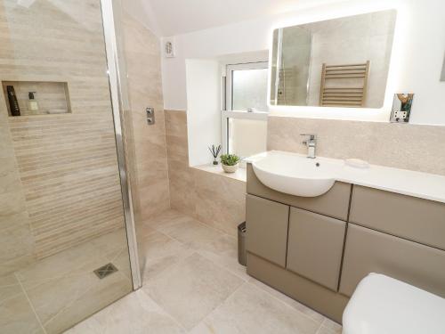 a bathroom with a shower and a sink and a mirror at 4 Castle View in Barnoldswick
