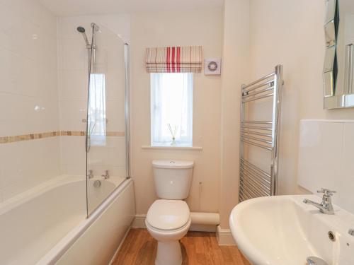 a white bathroom with a toilet and a sink at 7 Malt House Court in Watchet