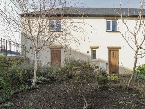 a white house with wooden doors in a yard at 7 Malt House Court in Watchet
