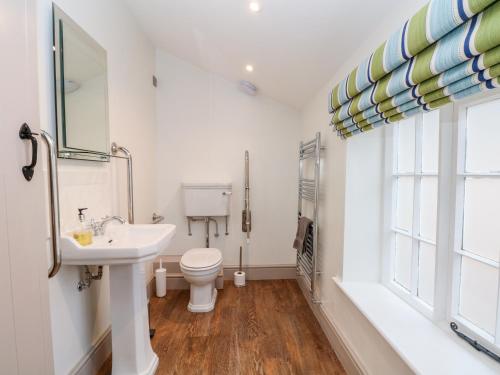 a bathroom with a sink and a toilet and a window at Lakeside Village & The Potting Shed in Macclesfield