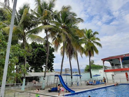 a pool with palm trees and a blue slide at Hotel Sael in Tocaima