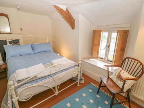 a bedroom with a bed and a chair and a window at Turnpike Cottage in Bideford