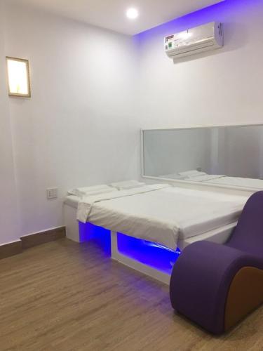a bedroom with two beds and a purple chair at Hotel MAI TUAN Phạm Hùng in Ấp Trường Huê