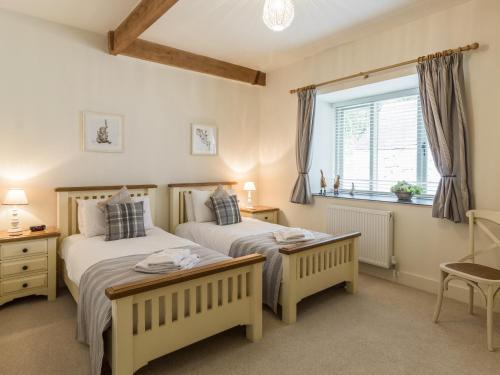two twin beds in a bedroom with a window at Sawmill Cottage in Belford