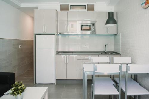 a kitchen with white cabinets and a table and chairs at FAMILY HOUSE MASPALOMAS II in Playa del Ingles