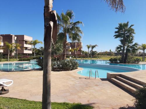 een zwembad in een resort met een palmboom bij Prestigia appartement opale in Marrakesh