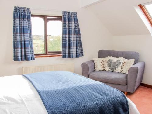 a bedroom with a bed and a chair and a window at Court Farm in Kidderminster