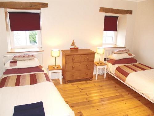 une chambre avec deux lits et deux fenêtres dans l'établissement Stable Cottage, Cardigan, à Cardigan