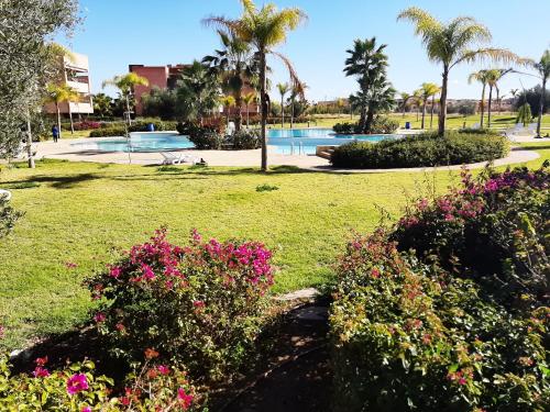 een park met bloemen en een zwembad bij Prestigia appartement opale in Marrakesh