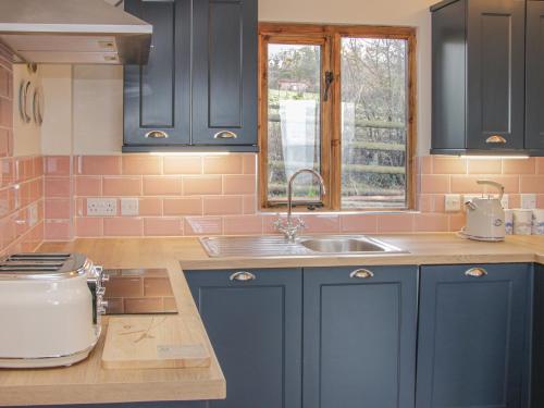 a kitchen with blue cabinets and a sink and a window at Hillside Lodge in Ludlow