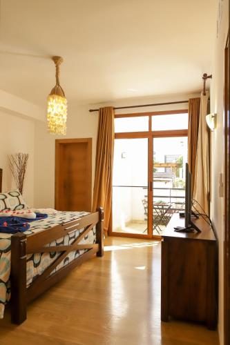 a bedroom with a bed and a television and a sliding glass door at Sybaris Suites & Residences in Juan Dolio
