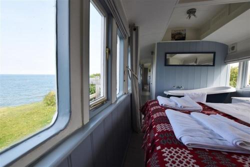 a bedroom with two beds and a view of the ocean at Clifftop Carriage in Aberporth