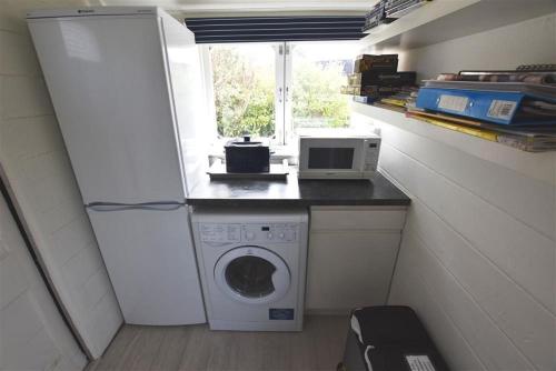 a small kitchen with a washing machine and a microwave at Clifftop Carriage in Aberporth