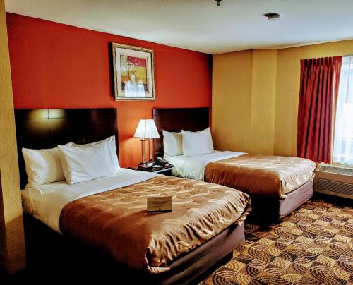 two beds in a hotel room with red walls at Quality Inn Brunswick Cleveland South in Brunswick
