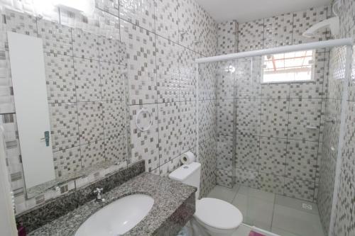 a bathroom with a sink and a toilet and a mirror at Pousada Vovó Dilma in Penha