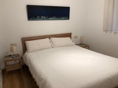 ein Schlafzimmer mit einem weißen Bett und zwei Nachttischen in der Unterkunft EL RINCÓN de LOLI - Lic UAT607 in Pamplona