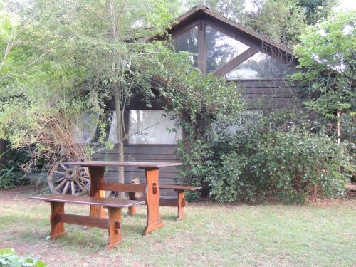 a picnic table and bench in front of a cabin at Aldea del bosque in Villa Ventana