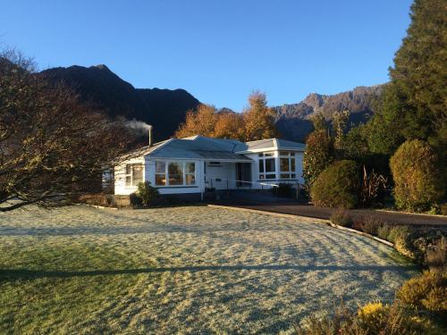 une maison blanche avec une grande allée. dans l'établissement Rainforest Motel, à Glacier Fox