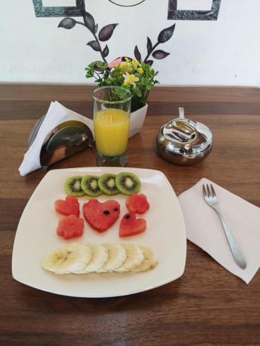 a plate of fruit on a table with a glass of orange juice at Hotel Cabañas El Rincón de las Campanas in Nobsa