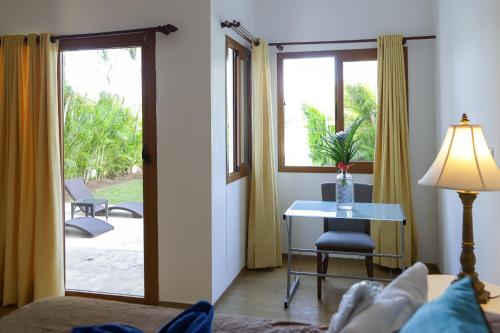 a living room with a table and a desk with a window at Sybaris Suites & Residences in Juan Dolio