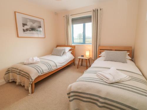 two beds in a room with a window at Atlantic Reach in Bude