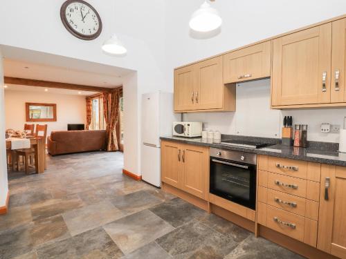 a kitchen with wooden cabinets and a clock on the wall at The Old Cart House in Oswestry