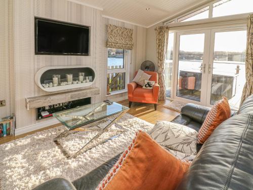 a living room with a leather couch and a television at Shore Beats Work - Capenwray 10 in Carnforth