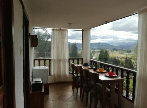 a dining room with a table and chairs and a large window at Hotel Cabañas El Rincón de las Campanas in Nobsa