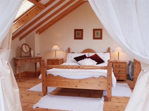 Un dormitorio con una gran cama de madera con sábanas blancas. en Dan Castell Cottage en Llandeilo