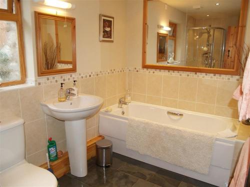 y baño con lavamanos, bañera y lavamanos. en Dan Castell Cottage en Llandeilo