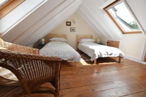 - une chambre mansardée avec 2 lits et une fenêtre dans l'établissement Cwmbrandy Cottage, à Fishguard