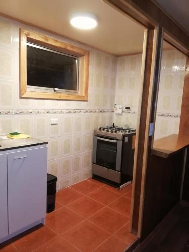 a small kitchen with a stove and a window at Cabaña Vista al Lago in Llanquihue