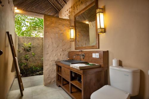 La salle de bains est pourvue de toilettes et d'un lavabo avec miroir. dans l'établissement The Mesare Eco Resort, à Nusa Penida