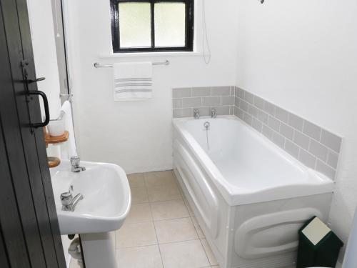 a white bathroom with a tub and a sink at An Teach Ban in Rossaveel