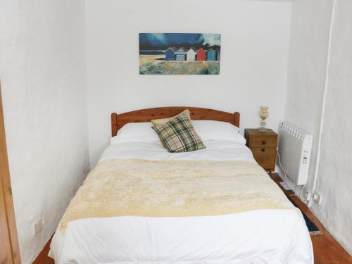 a bed in a bedroom with a picture on the wall at An Teach Ban in Rossaveel