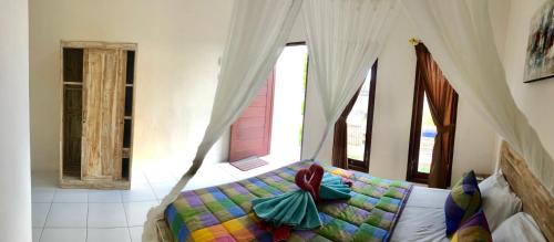 a bedroom with a bed with a canopy and windows at Jordan Guest House in Uluwatu