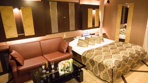 函館市にあるレステイ SakuRa（大人専用）のベッドとソファ付きのホテルルーム