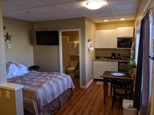 a bedroom with a bed and a table and a kitchen at Nimpkish Hotel in Alert Bay