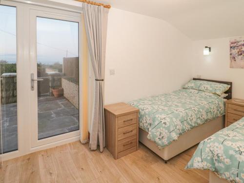 a bedroom with a bed and a sliding glass door at Ysgubor Ddegwm Bach in Beaumaris