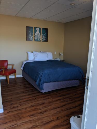 - une chambre avec un grand lit et une chaise rouge dans l'établissement Nimpkish Hotel, à Alert Bay