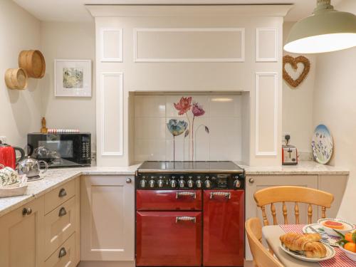 a kitchen with a red stove top oven next to a table at Rookwood in Exeter