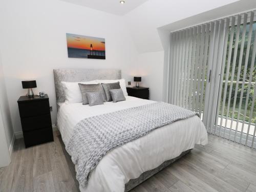 a white bedroom with a bed and a window at The Office Gardens, Apartment 3 in Whitby