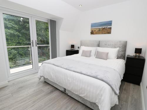 a white bedroom with a large bed and windows at The Office Gardens, Apartment 3 in Whitby