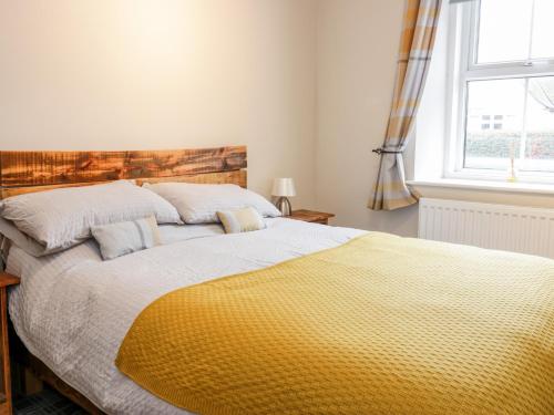 um quarto com uma cama grande e um cobertor amarelo em Victoria Cottage em Berwick-Upon-Tweed