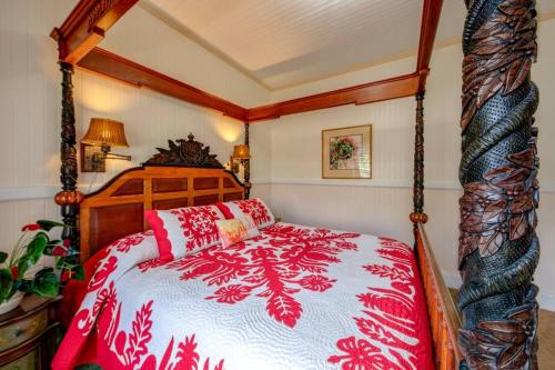 a bedroom with a red and white comforter on a bed at Ola'a House by Volcano Heritage Cottages in Volcano
